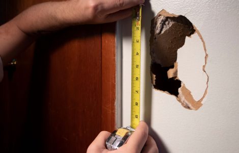 Un homme mesure la longueur d’un trou à l’aide d’un mètre ruban