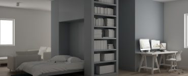 Une chambre grise avec un lit escamotable et un coin bureau
