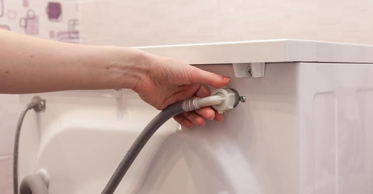 Zoom sur la main d'une femme retirant l'alimentation en eau de la machine à laver