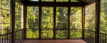 Vue sur la forêt à travers une grande véranda avec parquet en bois