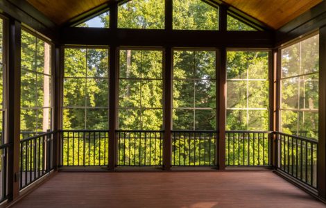 Vue sur la forêt à travers une grande véranda avec parquet en bois