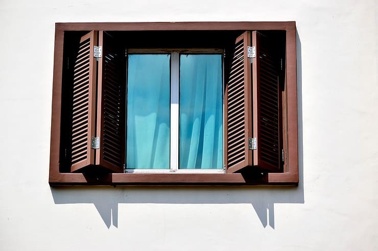 Vue extérieure sur une fenêtre en bois ouverte et une fenêtre vitrée intérieure