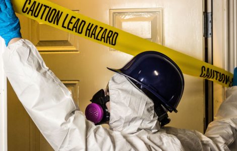 Un homme en combinaison et masque installe un signal d'avertissement de danger au plomb