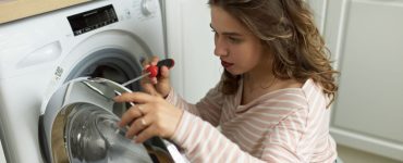 Une femme avec un tournevis réparant la machine à laver