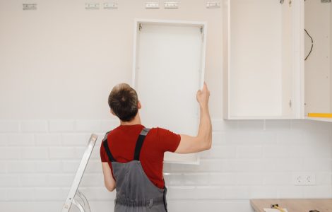 Un homme installant un placard de cuisine blanc