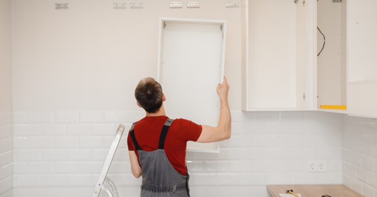 Un homme installant un placard de cuisine blanc