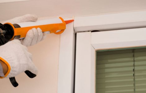 Main d'un homme utilisant un pistolet à calfeutrage manuel sur une fenêtre