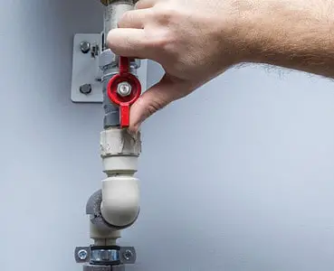 Zoom sur la main d’un homme tournant la vanne d’un tuyau