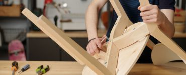 Vue sur un homme en train de resserrer les boulons de fixation d’une chaise en bois