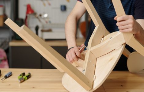 Vue sur un homme en train de resserrer les boulons de fixation d’une chaise en bois