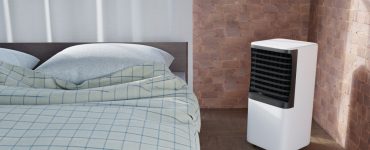 Un climatiseur portable placé à côté d'un lit