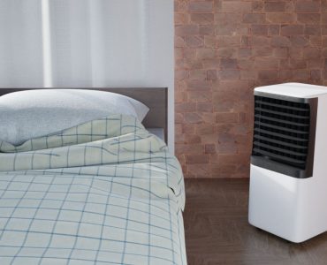 Un climatiseur portable placé à côté d'un lit