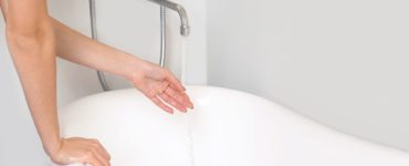 Une femme remplissant la baignoire teste la température de l'eau