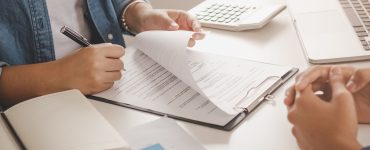 Une femme signant un contrat devant un agent