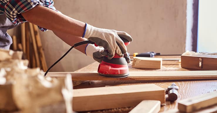 Une personne en train de poncer du bois dans un atelier de bricolage