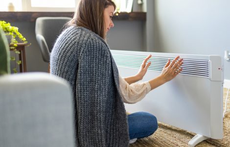 Femme se réchauffant les mains près du chauffage électrique