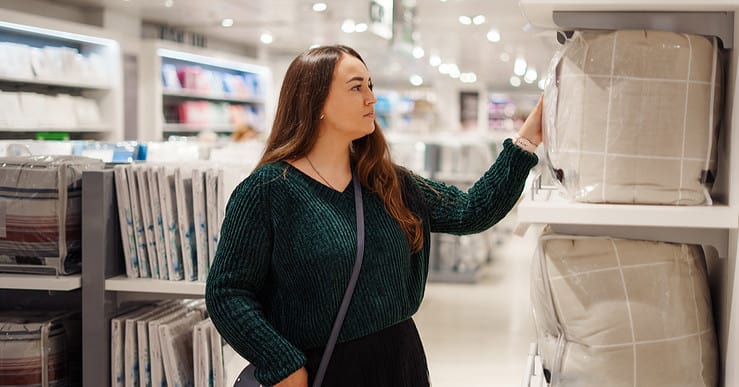 Une femme concentrée sur un article dans le rayon literie