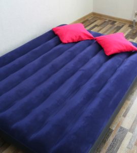 Un matelas gonflable bleu posé sur le parquet