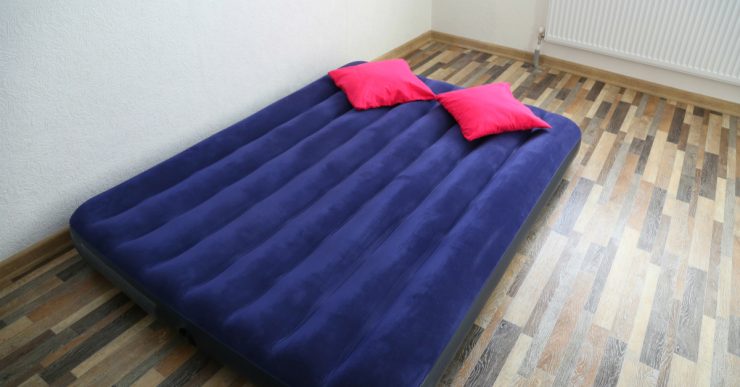 Un matelas gonflable bleu posé sur le parquet