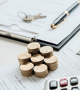 Illustation d'un prêt immobilier avec une maquette de maison, des pièces, une calculatrice et un contrat sur la table