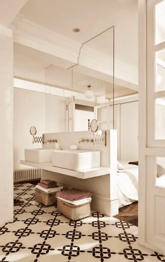 Une demi-cloison surmontée d'une vitre qui sert de meuble vasque et de tête de lit dans une suite parentale