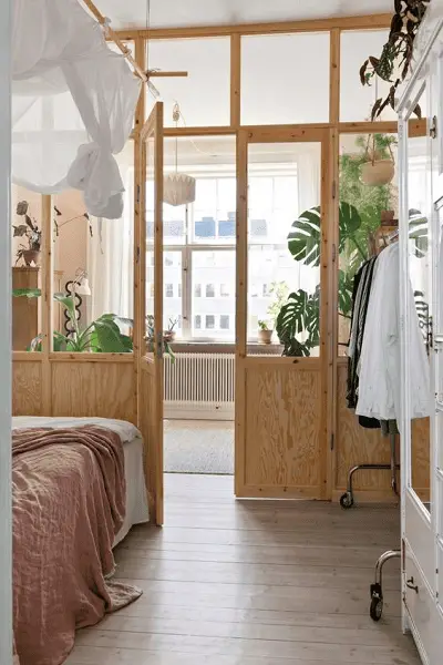 Une grande verrière en bois pour séparer la chambre conjugale du salon dans un petit appartement