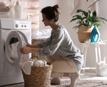 Une femme récupère la lessive terminée dans un panier en fibres