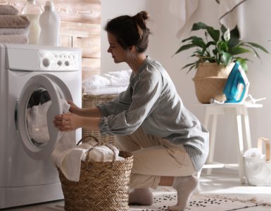 Une femme récupère la lessive terminée dans un panier en fibres