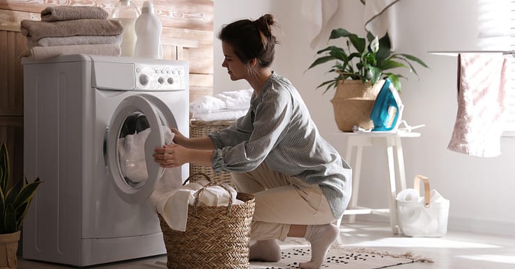 Une femme récupère la lessive terminée dans un panier en fibres