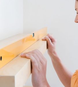 Une femme vérifie que l’étagère est horizontale à l’aide d’un niveau à bulle