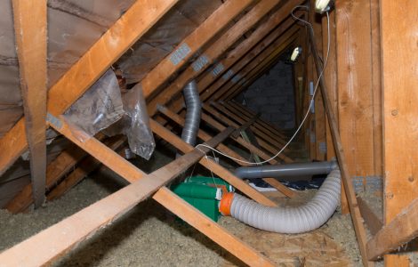 Des gaines grises passent dans la sous-toiture en bois d'une maison