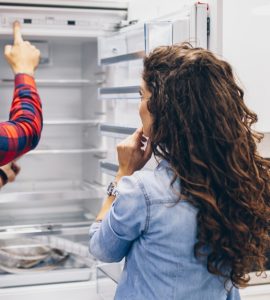 Un homme et une femme choisissant un frigo dans un magasin d'électroménagers