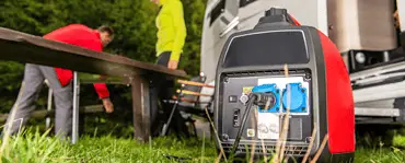 Un groupe électrogène posé sur le gazon avec une femme et un homme en fond