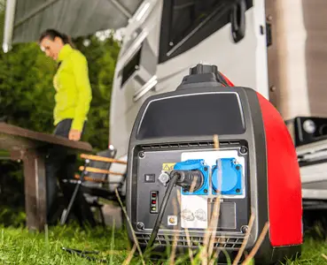 Un groupe électrogène posé sur le gazon avec une femme et un homme en fond