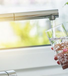 Zoom sur la main d'une femme en train de remplir un verre d'eau du robinet