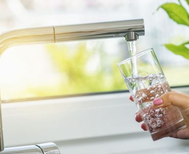 Zoom sur la main d'une femme en train de remplir un verre d'eau du robinet