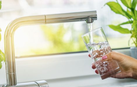 Zoom sur la main d'une femme en train de remplir un verre d'eau du robinet