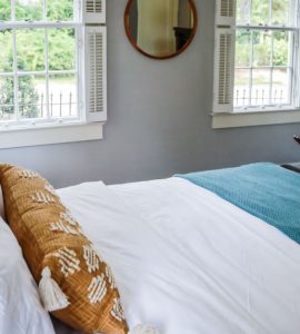 Une chambre avec un grand lit et deux fenêtres blanches