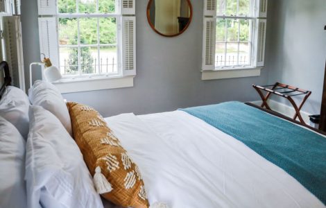 Une chambre avec un grand lit et deux fenêtres blanches