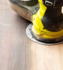 Un appareil de ponçage électrique posé sur une plaque ou un meuble en bois