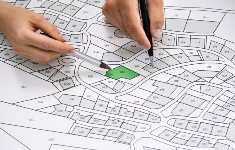 Zoom sur les mains de deux personnes montrant une parcelle sur un plan