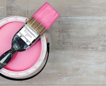 Vue de dessus sur un pot de peinture rose et un pinceau