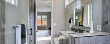 Une salle de bain moderne grise avec un grand miroir