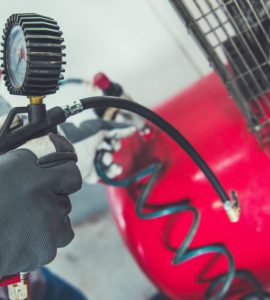 Un homme en gants noris se prépare à utiliser un compresseur d'air