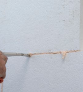 Zoom sur un homme plaçant un joint en silicone sur les feuilles d'isolation en polystyrène