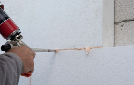 Zoom sur un homme plaçant un joint en silicone sur les feuilles d'isolation en polystyrène