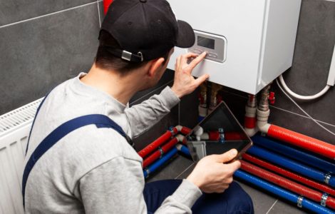 Un homme en combinaison de travail et avec une tablette à la main vérifie le système de chauffage