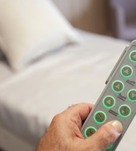 Main d'un homme tenant la télécommande d'un lit motorisé