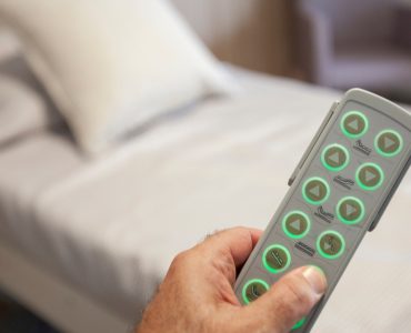 Main d'un homme tenant la télécommande d'un lit motorisé