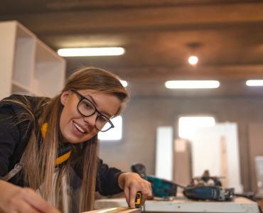 Une femme dans un atelier de menuiserie prend des mesures avec un mètre ruban